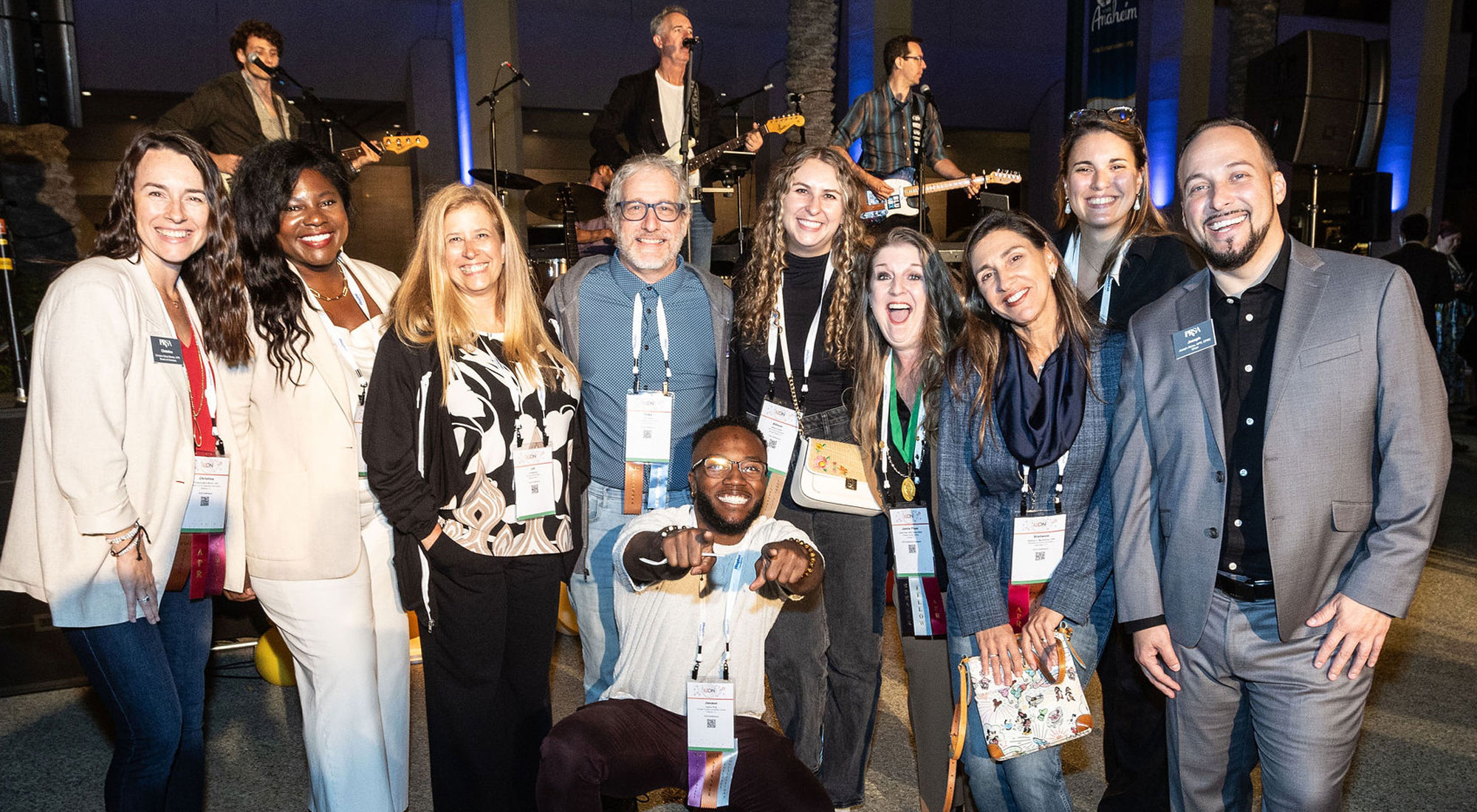 PRSA attendees group shot in front of rock band on stage PRSA attendees group shot in front of rock band on stage